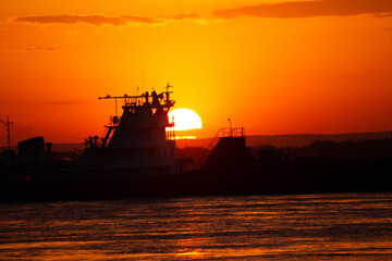 Ship on sunset, bright orange sun, big river