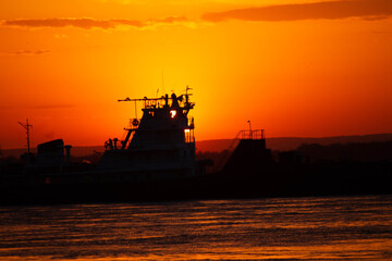 Ship on sunset, bright orange sun, big river