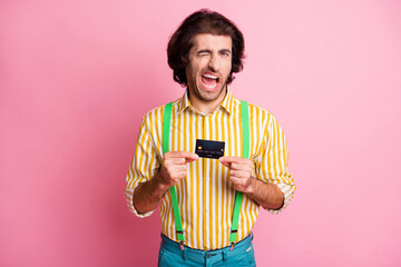 Photo of young handsome attractive male hold credit card blink wink eye wear suspenders isolated on...