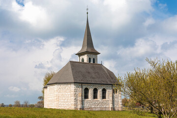 Fototapeta na wymiar Characteristic church in the green field in the Swiss Alps of the Canton Jura