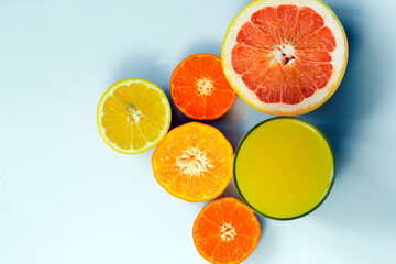 Sliced citrus on a white background with a glass of fresh juice. Grapefruit, lemon, tangerine