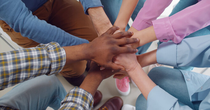 Multiracial people putting hands together in team meeting