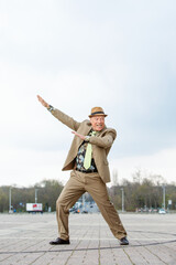 man in a brown suit from the 1980s dancing on the street