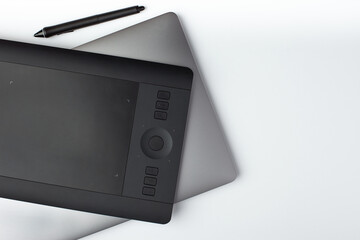 Top view photo of a graphic design tablet and laptop on a white background.