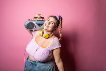 Young plus size woman isolated studio listening music laughing with headphones and stereo