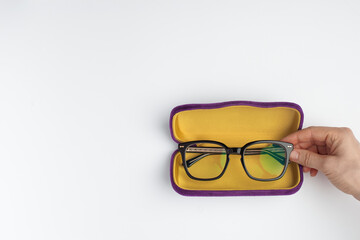 Eyeglasses lays in a case and holded by female hand on a white background