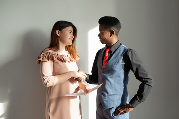 african man and caucasian woman shaking hands in the office 