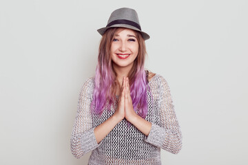 Happy positive female looking directly at camera, presses palms together, asking somebody, praying,...