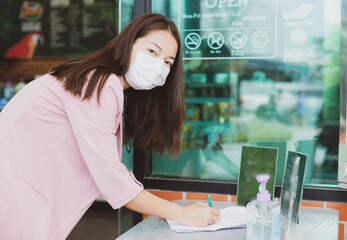 Asian woman register identity using a QR code or registration book before shopping to prevent the spread of Corona virus(Covid-19) at Cafe Amazon in PTT gas station