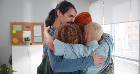 Multiethnic positive people hugging during therapy session in support meeting