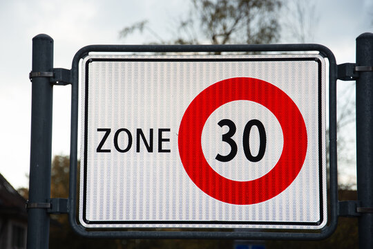 Die Nummer dreissig (30) in einem roten Kreis. Das Verkehrsschild zeigt eine 30er Zone.