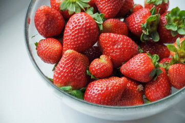 close up on a red strawberries in a glass bowl on the white background