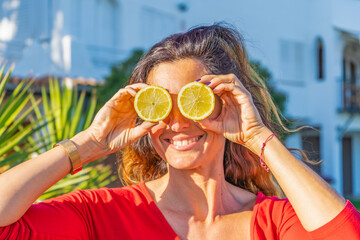 Happy woman holding lemons in front of eyes outdoor.Healthy food lifestyle, colorful fruits comic concept.