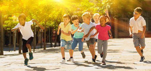 Group of joyful children running down the city street. High quality photo