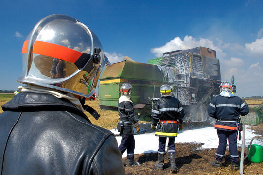 Incendie d'une moissonneuse dans un champ pendant une moisson de bl&eacute;. Intervention pompiers pour &eacute;teindre l'incendie