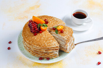 Delicious homemade crepe cake decorated with pomegranate seeds and mandarins.