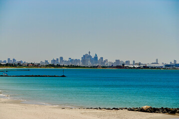 Southern view of the Sydney skyline on a hazy summer day, seen from the shoreline of Botany Bay in...