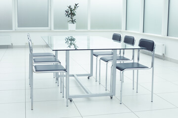Black chairs glass table in bright large studio office space. Workspace and Coworking