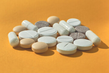 Lot of multicolored pills and tablets on orange background. Close up