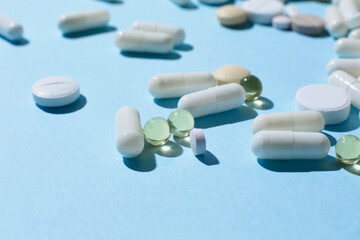 Lot of multicolored pills and tablets on blue background. Close up