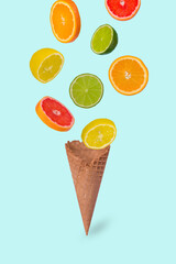 Minimal idea with ice cream cone and fresh orange, lime, lemon and grapefruit sliced, on pastel blue background.
