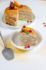 Delicious homemade crepe cake decorated with pomegranate seeds and mandarins.