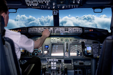 Rear view of caucasian male pilot sitting in aircraft cockpit and checking controls