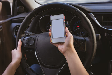 Midsection of caucasian woman driving a car, holding smartphone with blank screen