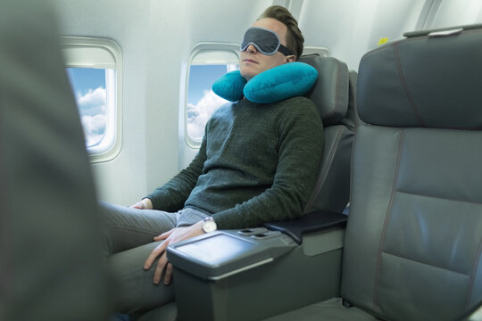 Caucasian Man With Neck Travel Cushion And Eye Mask Resting On Plane