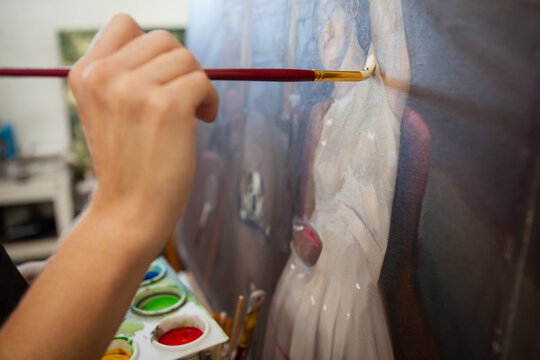 Close up of the hand of a caucasian woman working at a painting on an easel at an art studio