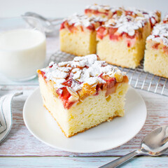 Homemade cake - yoghurt cake with rhubarb, sprinkled with almond flakes and powdered sugar.