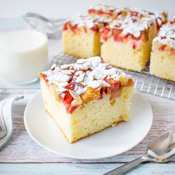 Homemade cake - yoghurt cake with rhubarb, sprinkled with almond flakes and powdered sugar.