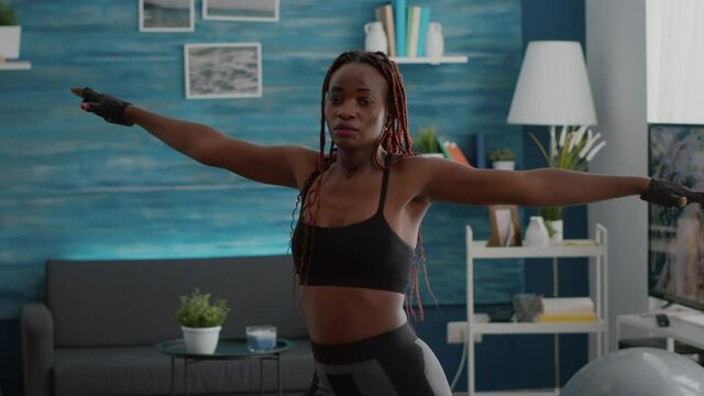 Athlete fit black woman wearing sportswear working body muscle doing legs exercices during morning workout in living room. Adult slim practicing fitness position enjoying healthy lifestyle