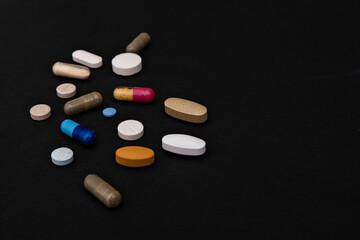 Close-up colorful powder soft capsules pill vitamin blue pink yellow brown supplements on black background