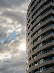 Obraz premium Detail of a facade of a building in an urban area with a cloudy sky in the background at sunset. Reflections and sun glare.