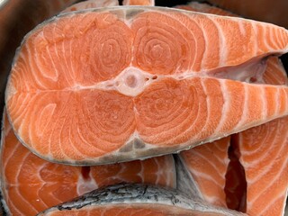 Sliced pieces of red fish. In a metal bowl, salmon steak. Salmon is prepared for baking over the fire.