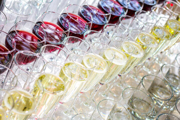 A lot of glasses with white wine and red wine glasses in a row.