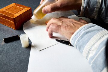Man's hands gluing a letter envelope