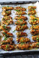 Sweet Chili Baked Chicken Wings. Freshly Cooked on Oven Tray with Sauce and Chopped Chives.