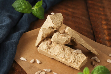 Natural vegan product. Sunflower halva on parchment paper on a wooden background with a blue napkin. Rustic style. Top view. Flat lay