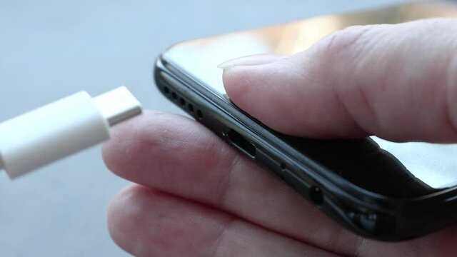 Woman plugging a USB type C cable into a smartphone connector to charge. Special charging connector for phone.