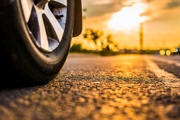 Sunset in the city, the headlights of approaching car on the highway. Close up view from the road level from the wheel of the car