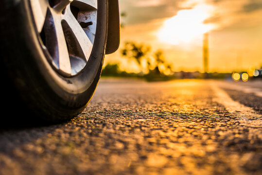 Sunset in the city, the headlights of approaching car on the highway. Close up view from the road level from the wheel of the car