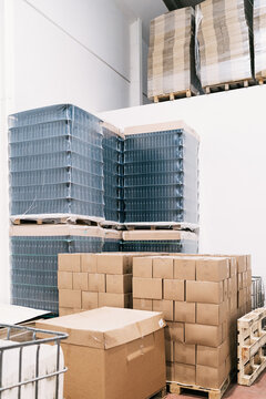 Warehouse with heaps of carton boxes and plastic containers with bottles of beer in factory