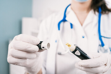 Crop unrecognizable female nurse in sterile gloves with blood sampling device at work in hospital