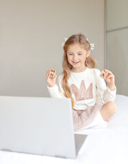 Happy little girl learning online with computer at home. Online school concept.