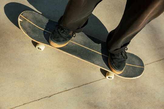 Close-up of the feet of a young man who is riding a skateboard in the street