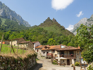 Fototapeta na wymiar Vistas del paisaje rural de San Esteban de Cuñaba en Asturias, con montañas altas al fondo, casas de piedra y árboles verdes alrededor, en medio de la naturaleza, en un entorno saludable, verano 2020