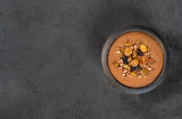 Vegan sweet soup puree of dried fruits, raisins, dates, nuts with cocoa in a wooden bowl on a dark gray background in rustic style top view copy space