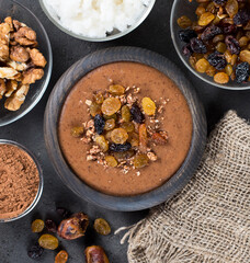 Soup puree of dried fruits, raisins, dates, nuts with cocoa in a wooden bowl on a linen napkin on a dark gray background in rustic style top view